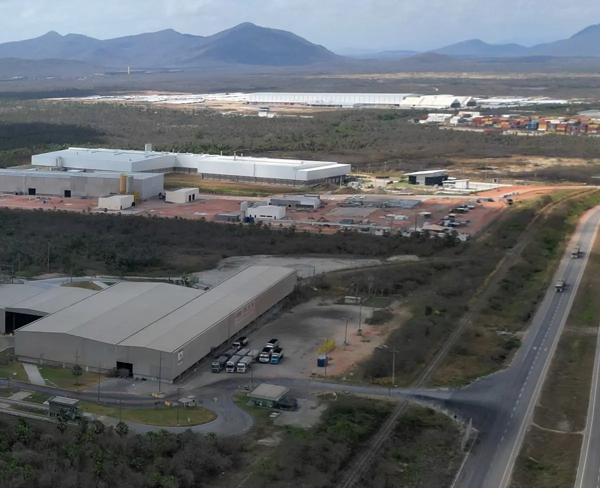 Fábrica de cimento com silos e galpões vista de longe