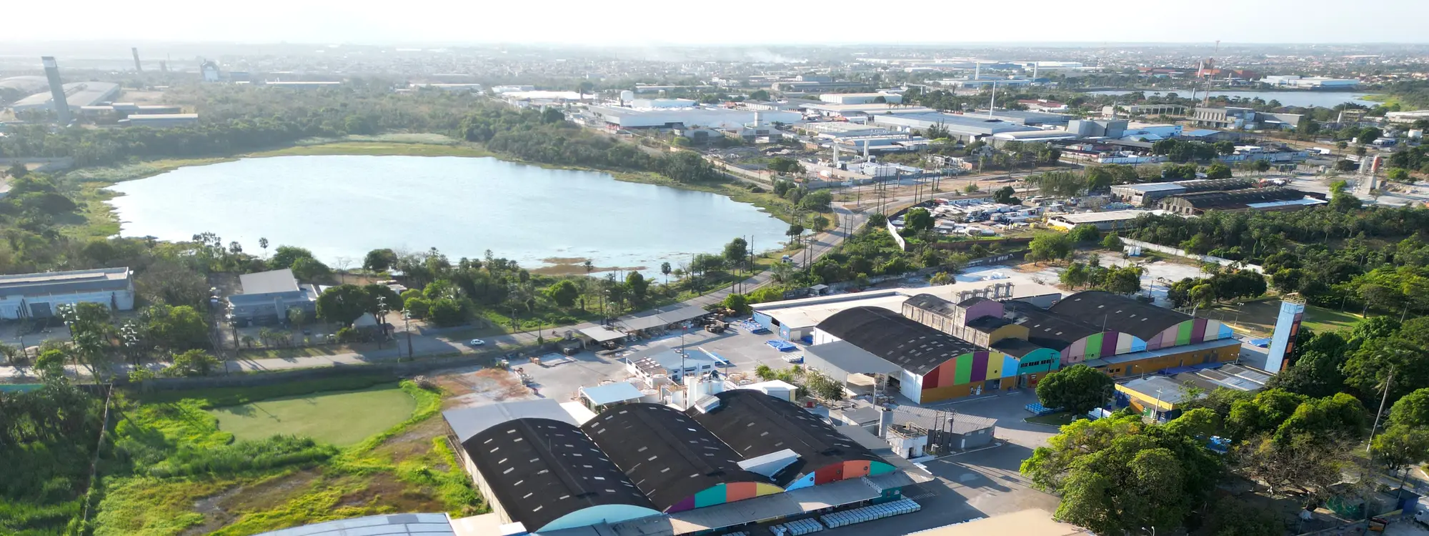 Bairro industrial com lagoa ao fundo, visto de drone