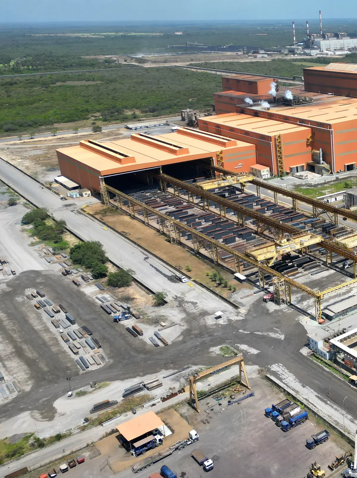 Fábrica com galpões laranja e esteiras vista do alto